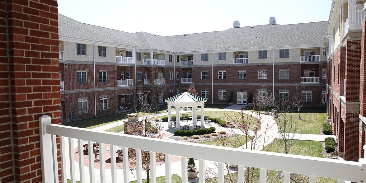 A serene courtyard view with a central gazebo surrounded by a multi-story residential building.