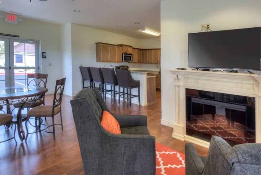A cozy open floor plan featuring a living room with a fireplace and TV, leading to a kitchen area with bar stools.