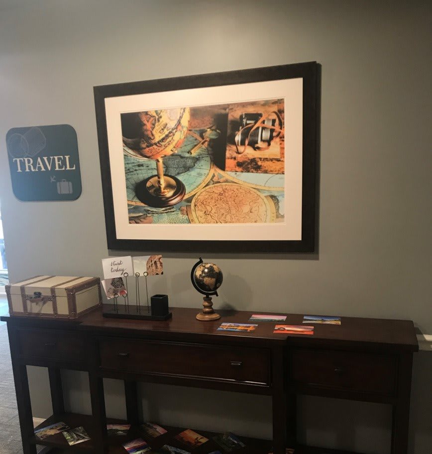 A travel-themed office area featuring a framed world map, a decorative globe, and travel brochures on a wooden table.