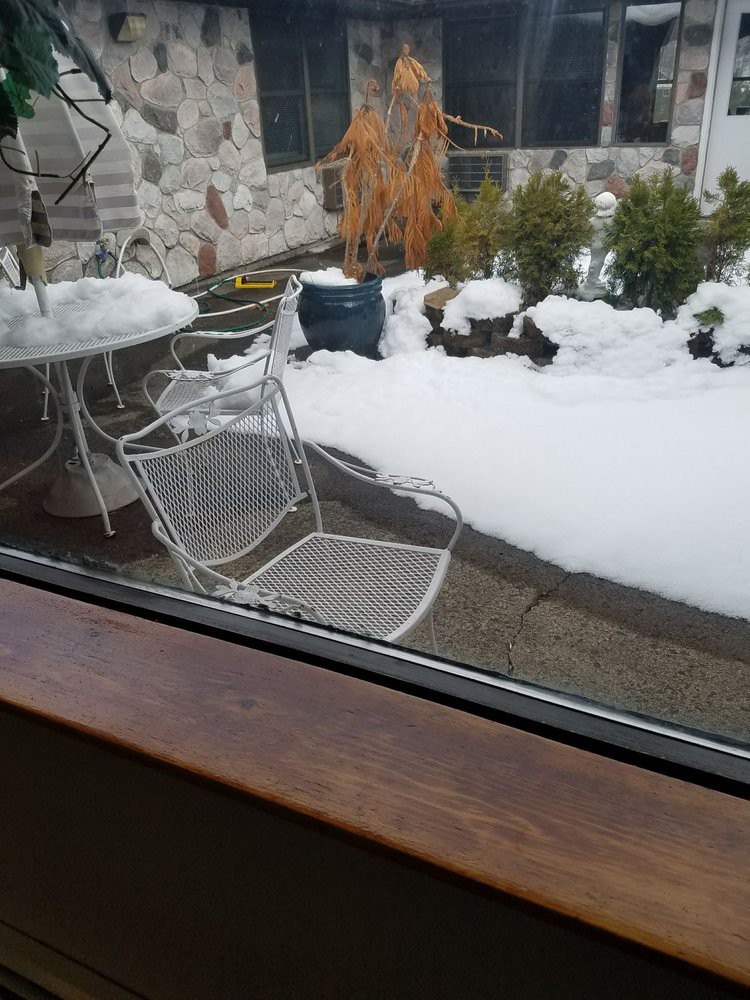 A snowy patio with outdoor furniture covered in snow.