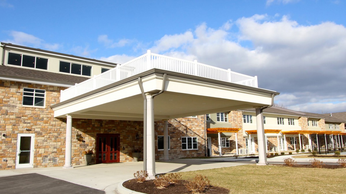 A modern building entrance with a covered canopy set against a blue sky.