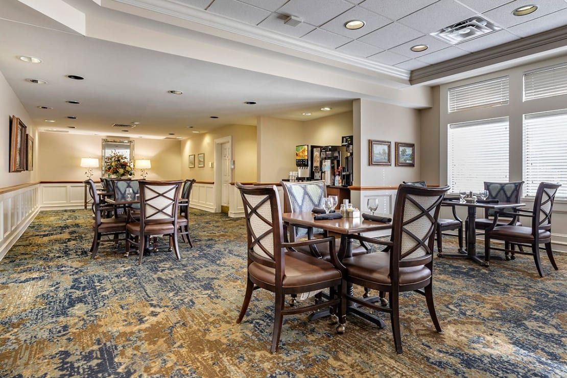 A cozy dining area with multiple tables and chairs, featuring a carpeted floor and elegant decor.
