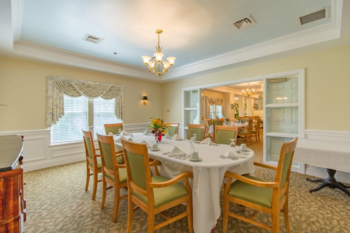 An elegant dining room with a beautifully set table and a chandelier overhead.