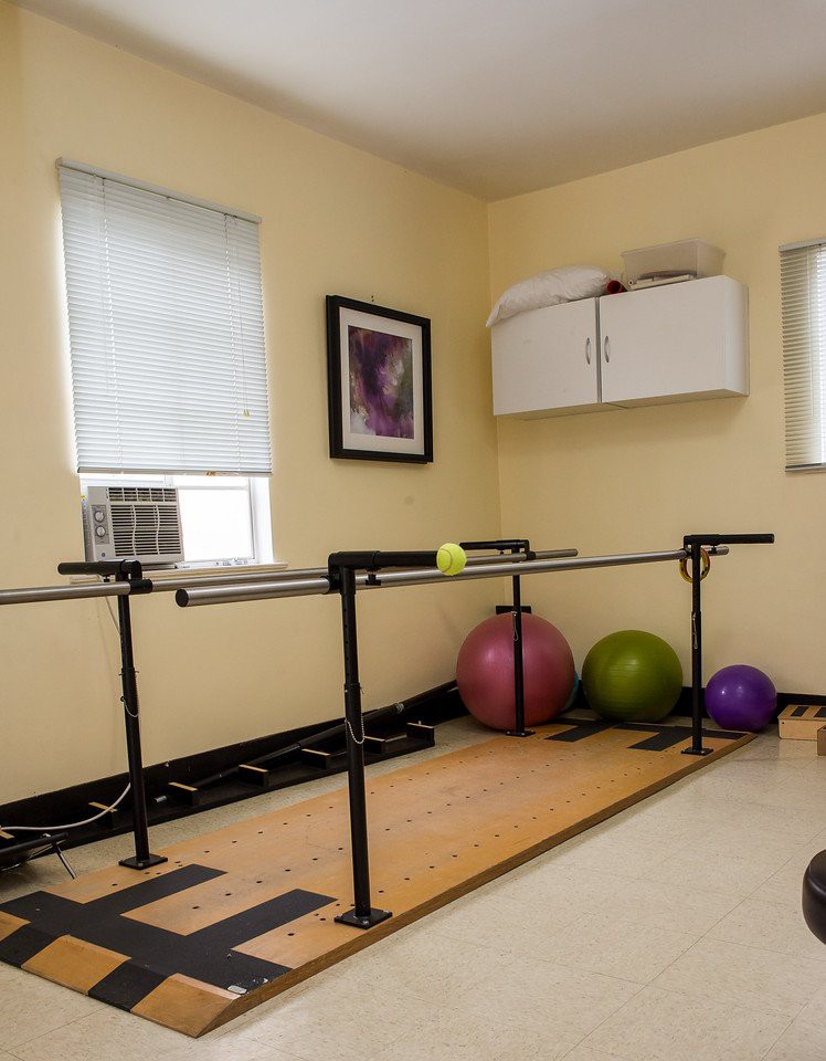 A rehabilitation room equipped with parallel bars and exercise balls for physical therapy exercises.