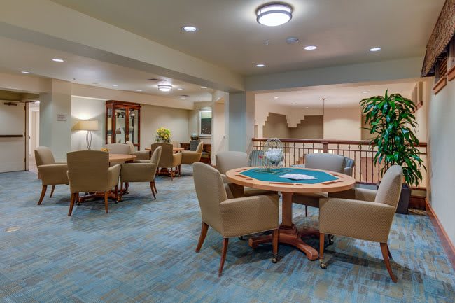 A cozy lounge area with comfortable seating and tables, warmly lit.