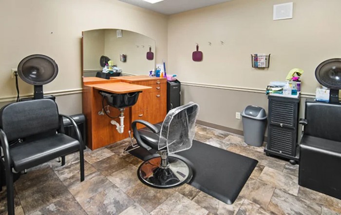 A well-equipped hair salon station featuring a styling chair, mirror, and storage cabinets.