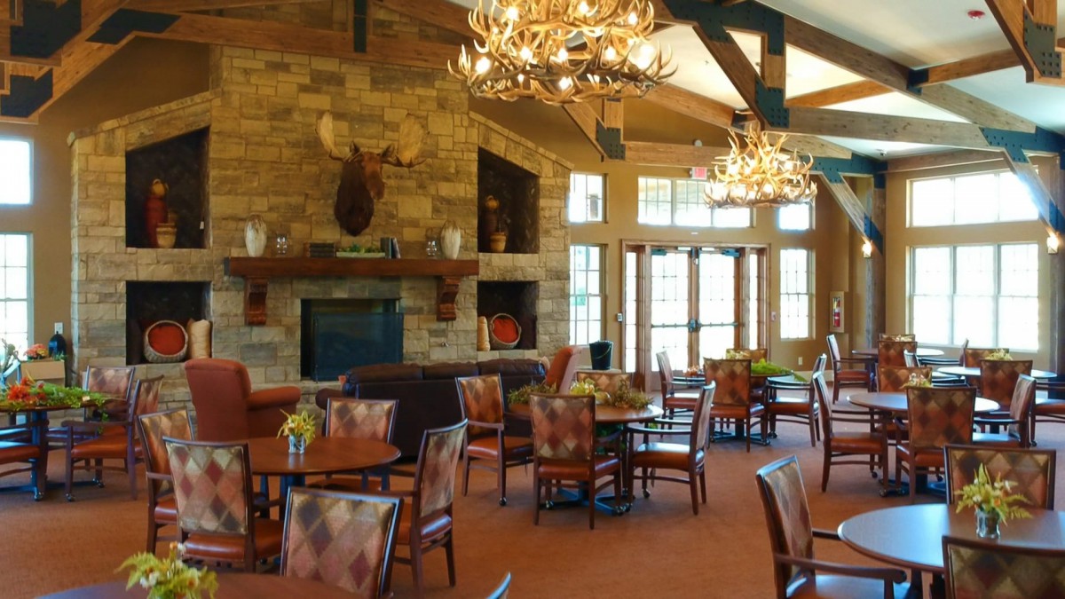 A cozy restaurant dining area with rustic decor, featuring chandeliers, wooden beams, and a fireplace.