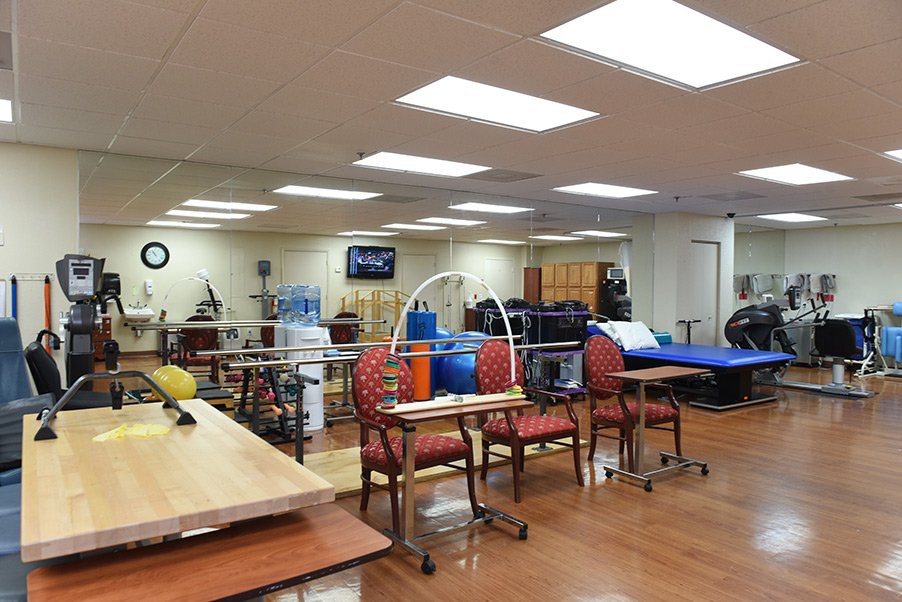 A well-equipped physical therapy and rehabilitation room with various exercise machines and equipment.
