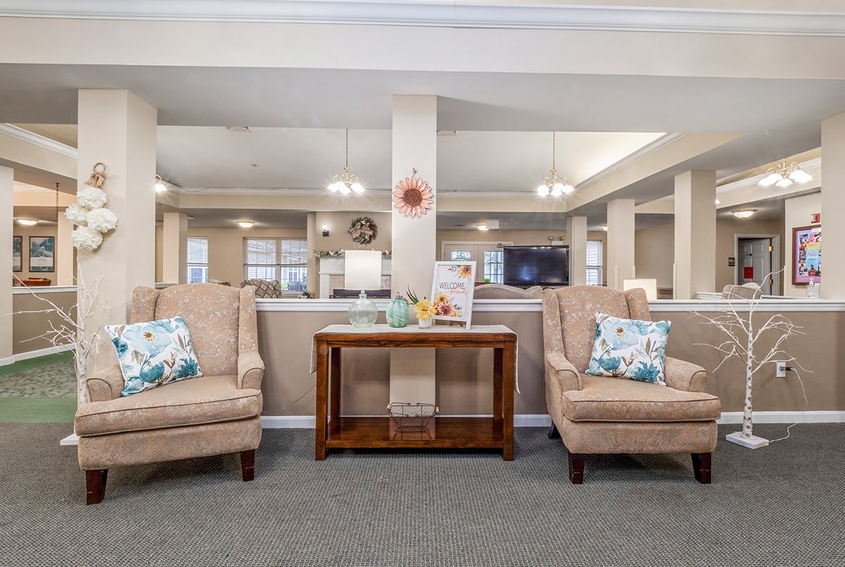 A cozy living room area with two upholstered chairs and a wooden table, adorned with decorative pillows and various decor pieces.