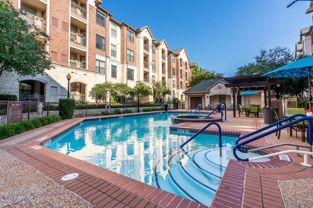 A modern apartment complex featuring an outdoor swimming pool.