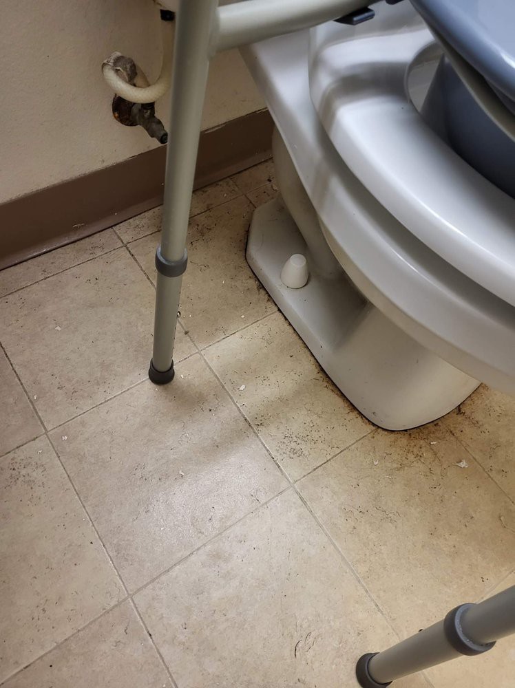 A bathroom scene with a toilet, tiled floor, and a mobility aid.
