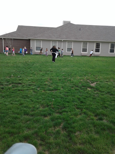Children enjoying outdoor playtime in a grassy area near a building.