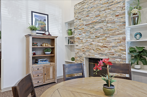 A cozy living area featuring a stone accent wall, wooden furniture, and decorative plants.