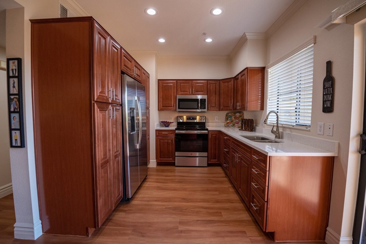 A modern kitchen with wooden cabinets, stainless steel appliances, and a hardwood floor.