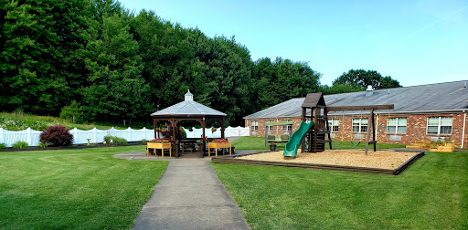 A vibrant playground area featuring a gazebo and slide, set in a spacious green lawn.