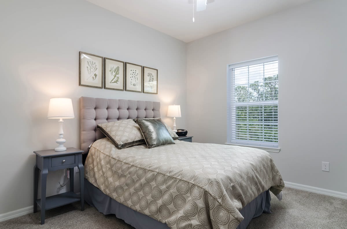 A cozy and well-decorated bedroom with a tufted headboard, elegant bedding, and framed artwork on the wall.