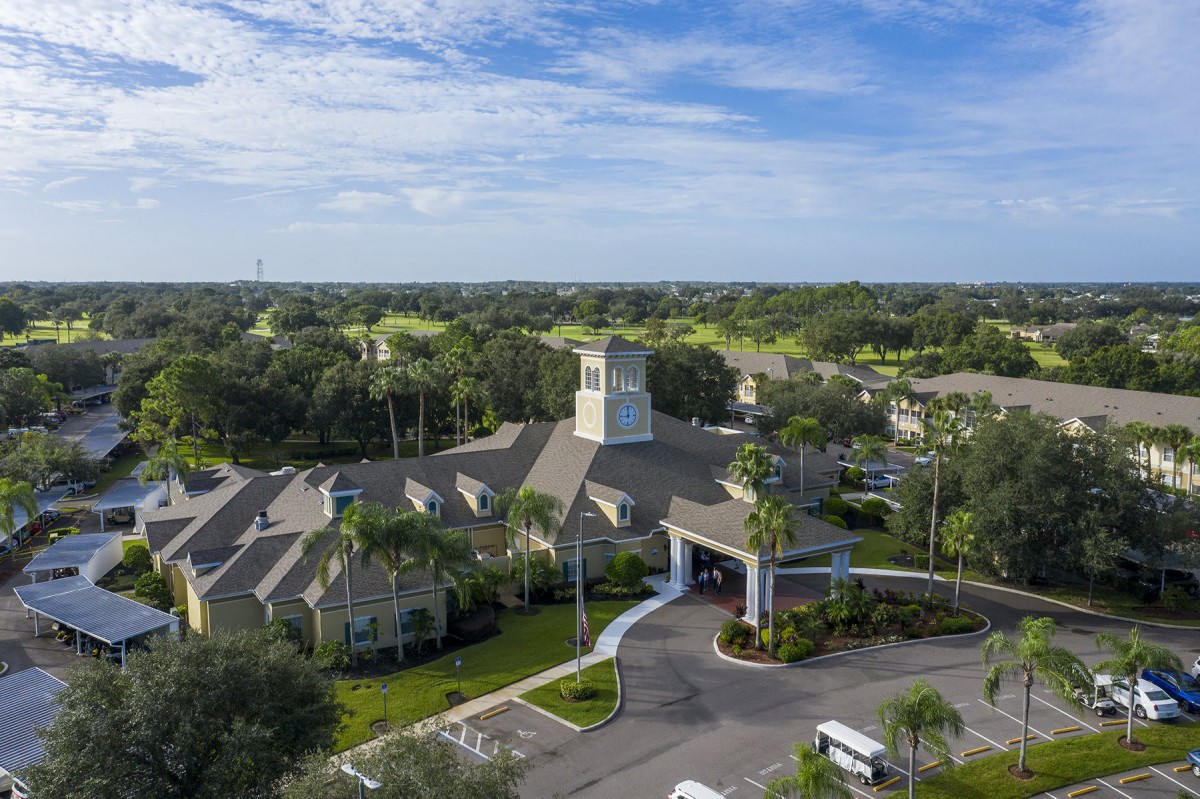 An aerial view of a large building surrounded by greenery and a clear blue sky.