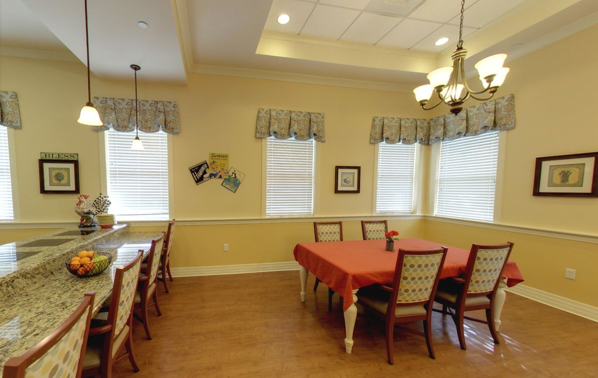 A cozy dining room with neatly arranged tables and chairs, illuminated by a chandelier.