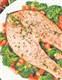 A plate of cooked salmon served with broccoli and tomatoes.