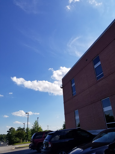 A clear blue sky with fluffy clouds beside a brick building.