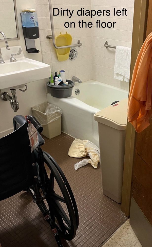An accessible bathroom with a wheelchair, sink, and bathtub.