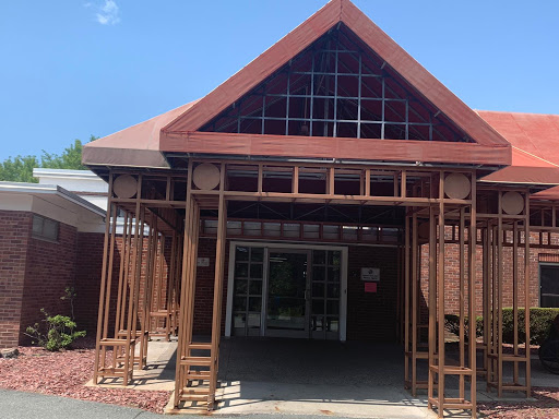 A striking modern wooden structure with a triangular roof, designed to create an inviting entrance.