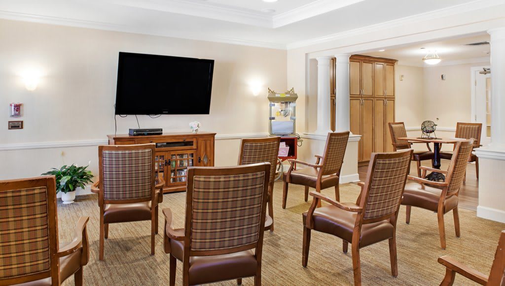 A small room with several wooden chairs arranged in front of a large television.