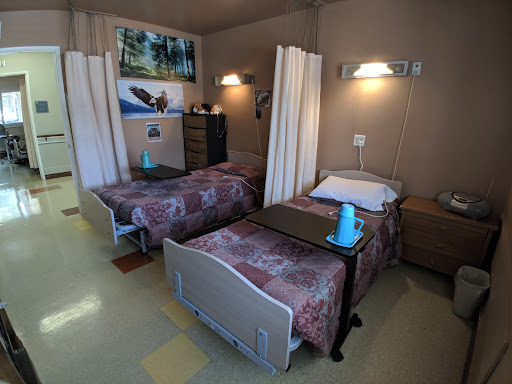 A shared hospital patient room featuring two beds, separated by curtains for privacy.
