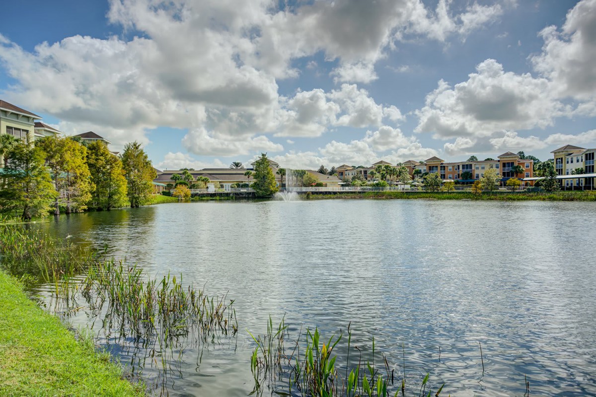 Serene lakeside view with houses under a cloudy sky.