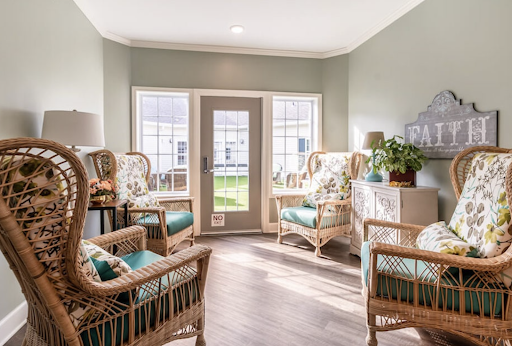 A bright and cozy seating area featuring rattan chairs and green walls, perfect for a relaxing afternoon.