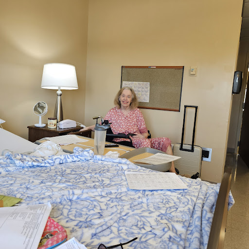 A patient sits comfortably in a hospital room, surrounded by personal items and a warm lamp lighting the space.