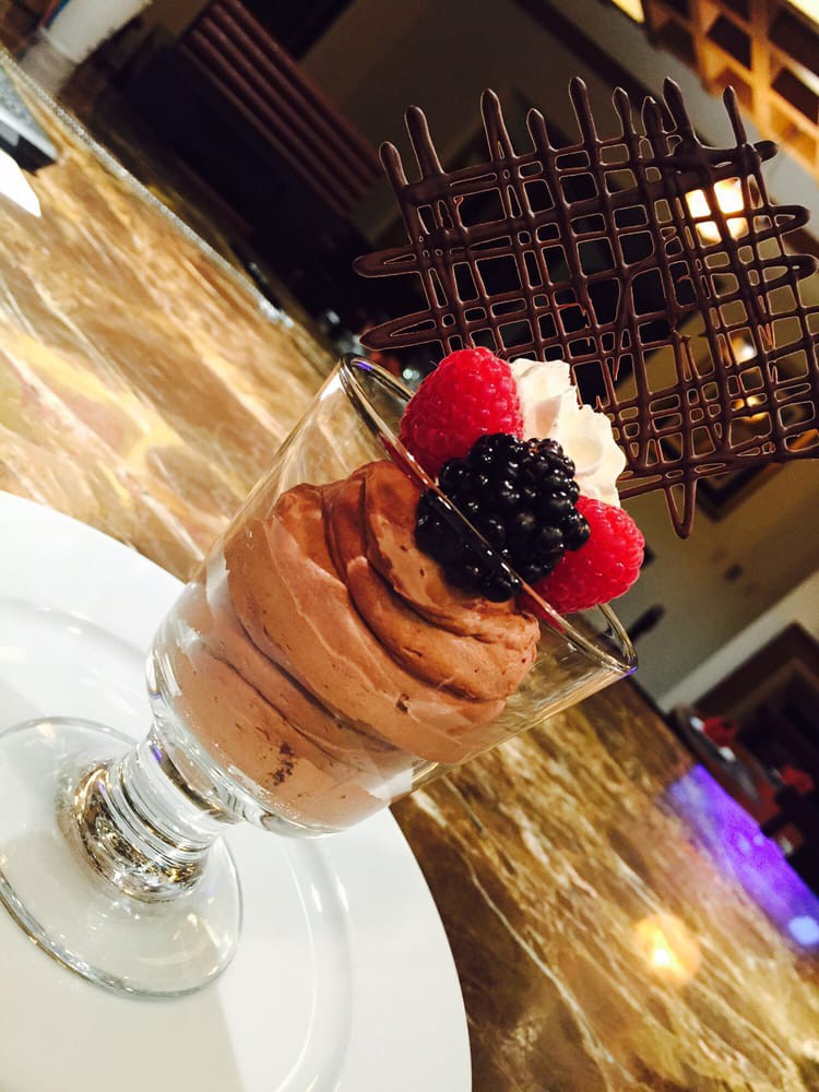 A delicious chocolate mousse topped with fresh berries, whipped cream, and a decorative chocolate lattice.
