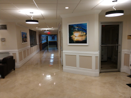 A well-lit hallway featuring artwork on the walls and polished flooring.