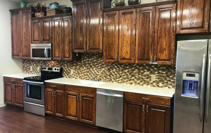 A modern kitchen with wooden cabinets and a mosaic backsplash, featuring stainless steel appliances.