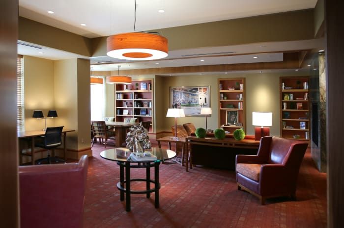 A cozy lounge area with comfortable seating, bookshelves, and warm lighting.