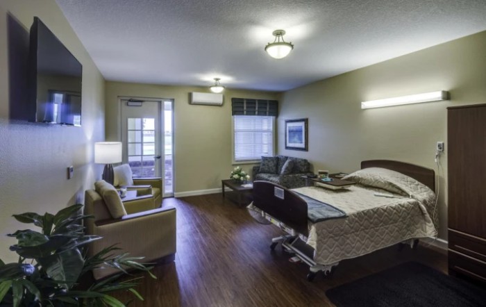 A well-furnished hospital or nursing home room with a bed, chair, and sofa.