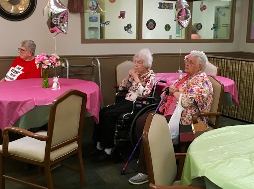 Two elderly women enjoying a social gathering in a decorated room.