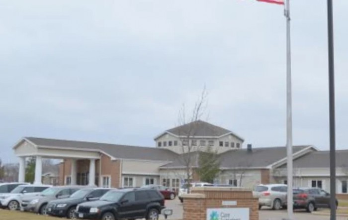 A view of a building with a parking lot full of cars on a cloudy day.