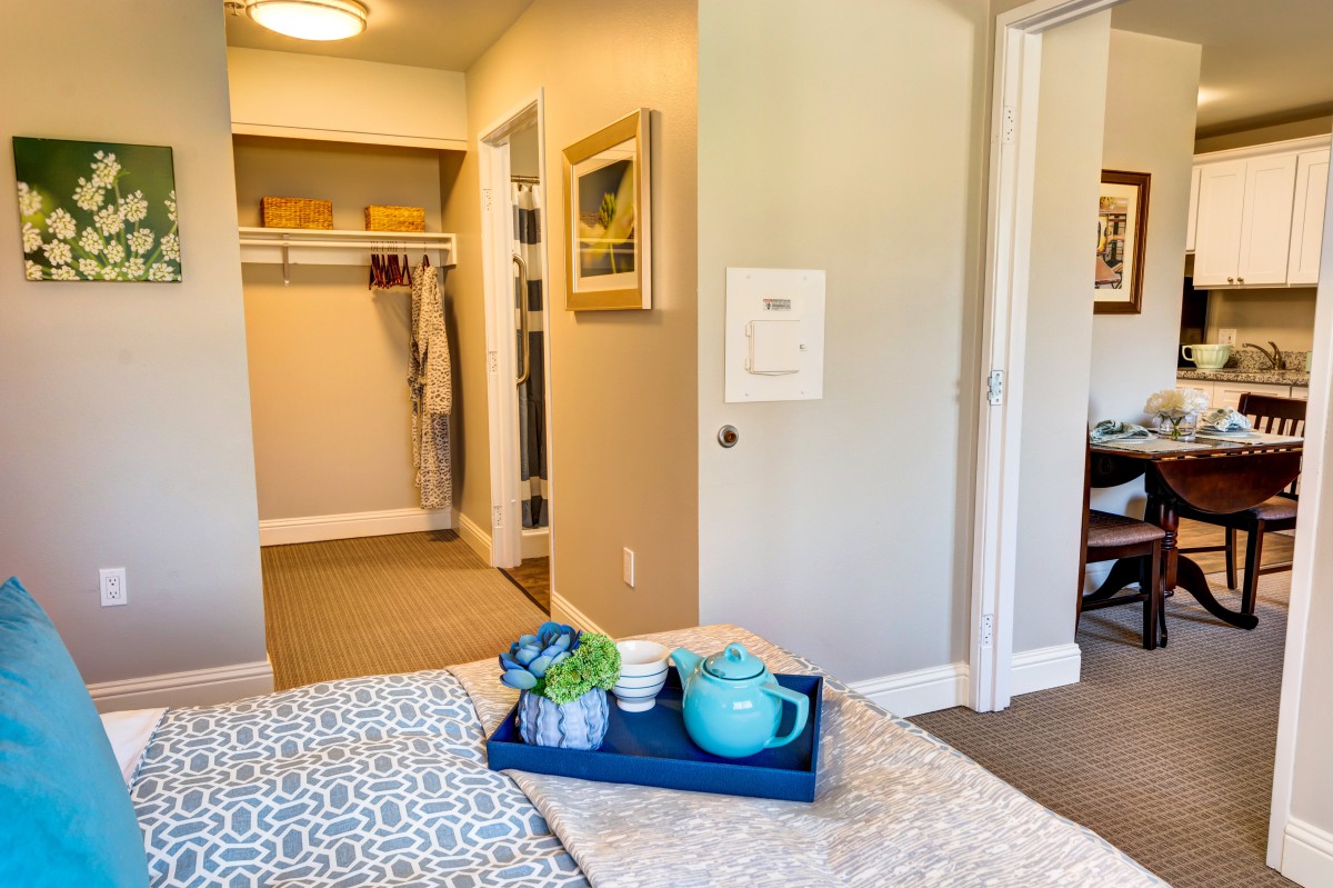 A cozy bedroom with a neatly arranged tea set on the bed and an open walk-in closet.