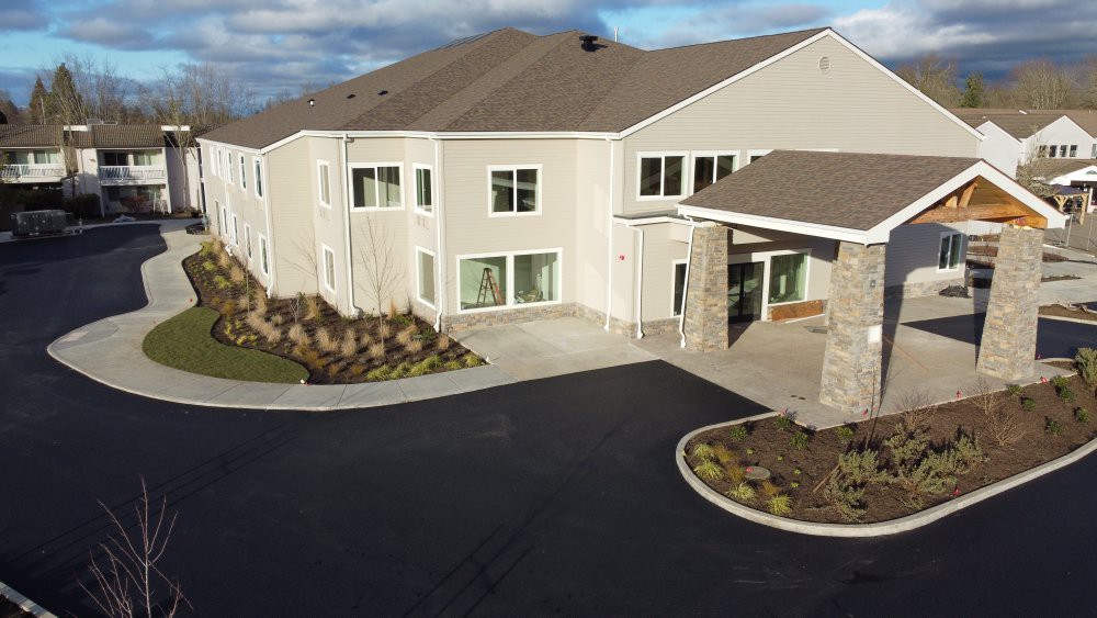 A modern residential building with a landscaped entrance and paved driveway.