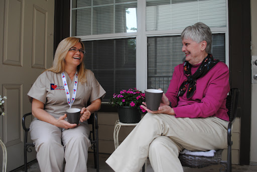 Two women enjoying a relaxed conversation with coffee on a porch.
