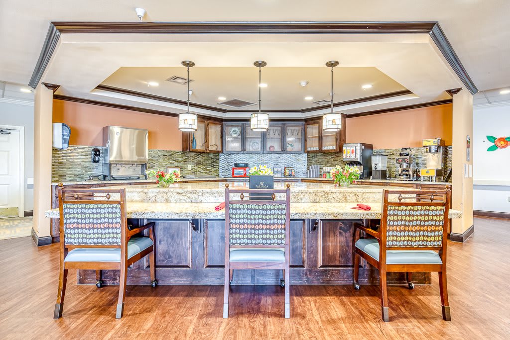 A modern kitchen interior with a wooden floor, countertop, and stylish chairs.