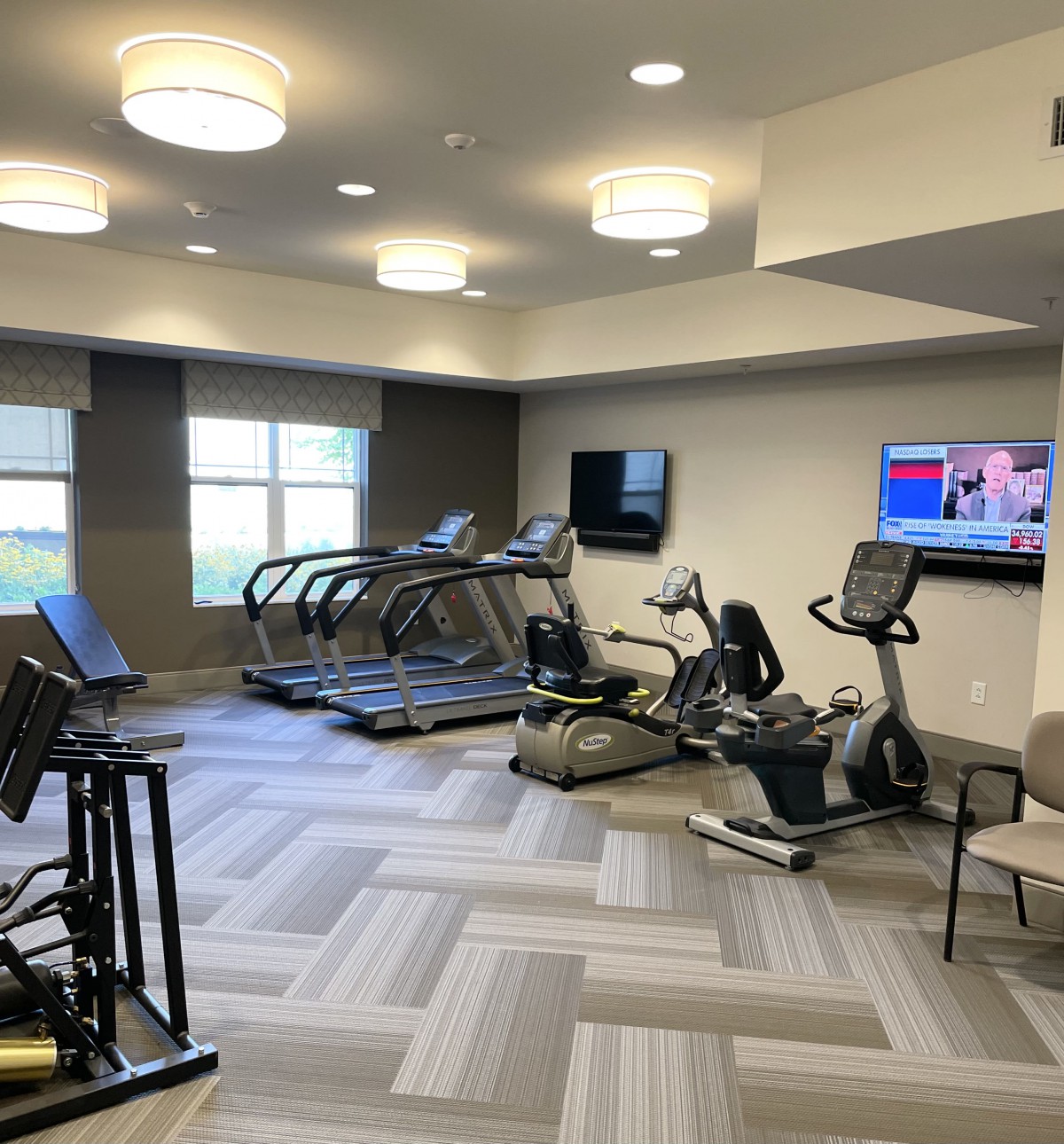 A modern gym with treadmills, stationary bikes, and televisions.