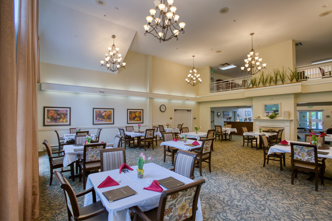 A spacious dining area featuring elegantly set tables and chandeliers.