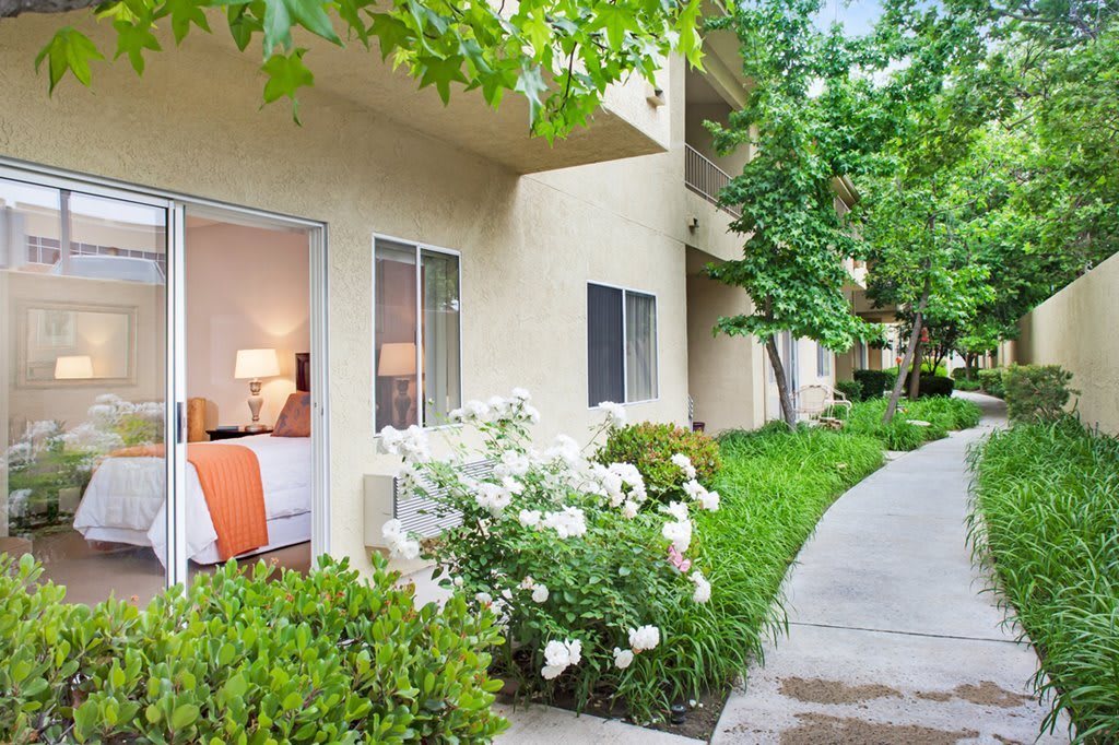 A peaceful apartment exterior with a garden and pathway.