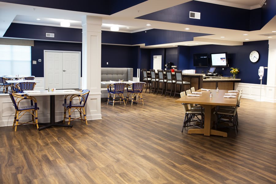 A modern restaurant interior featuring a spacious dining area with wooden floors and ample seating.