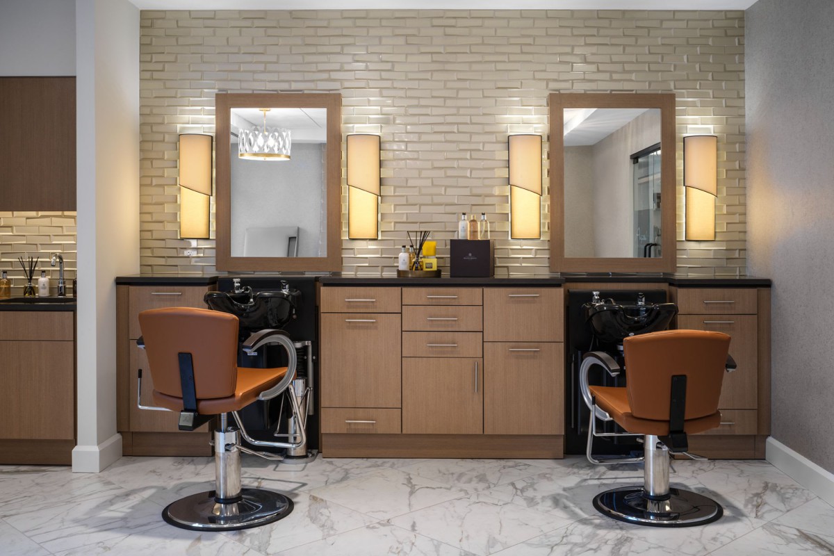 A modern hair salon interior with two barber stations, featuring mirrors and stylish chairs under warm lighting.