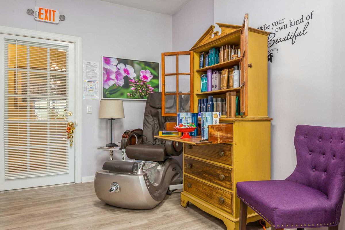 A cozy waiting room featuring a massage chair and wooden bookshelf filled with books.