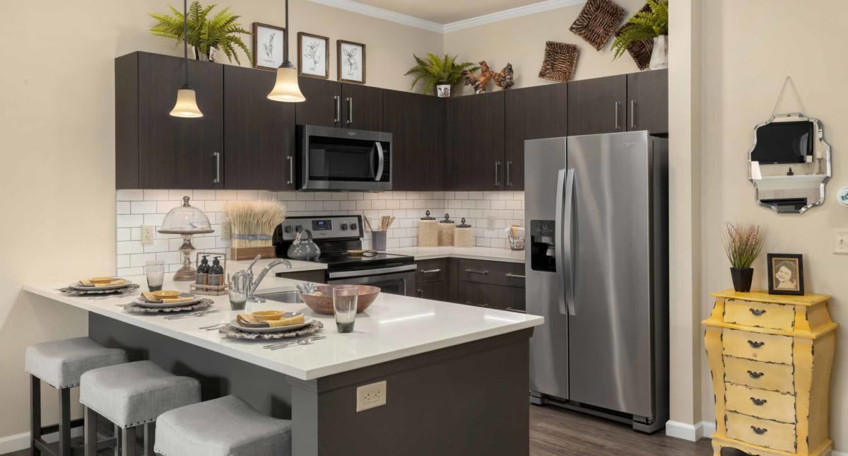 A modern kitchen with stainless steel appliances, dark cabinets, and a central island for dining and preparation.
