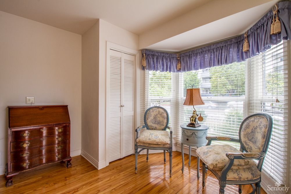 A cozy corner of a living room with antique chairs and a lamp by the window.